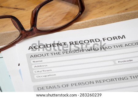 Accident report application form on brown envelope and eyeglass, business insurance and risk concept; document is mock-up