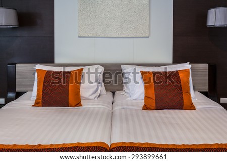 Red pillow on bedroom with white bed sheet and lamp light off