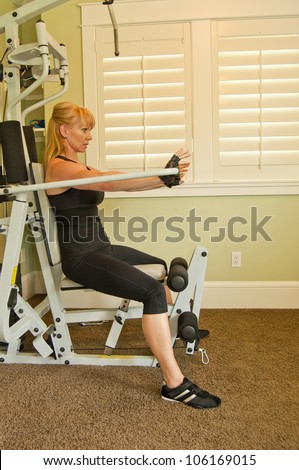 Attractive Caucasian woman using an exercise machine in a home gym.