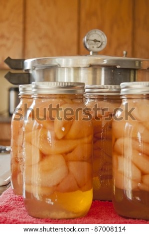 Glass jars of home canned pears with a pressure cooker