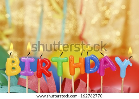 lit birthday candles in front of party items