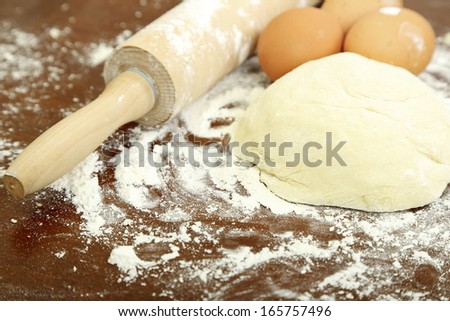 dough with rolling pin and eggs on table