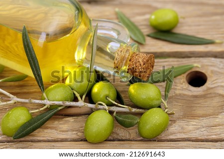 olive oil with branch of olive tree on wooden background