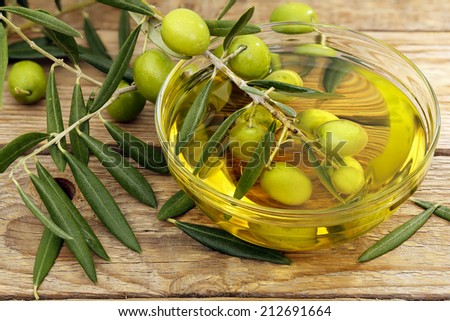 olive tree branch dipped in bowl of olive oil