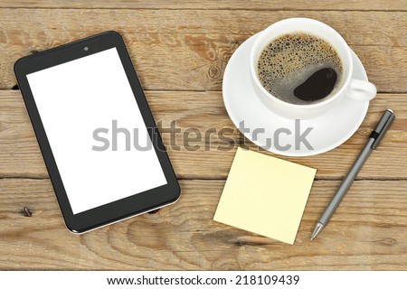 tablet pc, post it notes and cup of coffee on old wooden surface