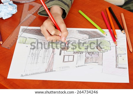 closeup of a boy's hand drawing a house interior