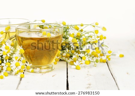 cup of chamomile tea with chamomile flowers on white wooden planks