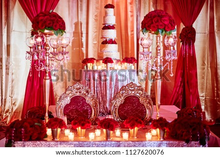 The seat for bride and groom of luxury indian wedding with wedding cake in background decoration with red roses theme and candle light in the sangeet night party