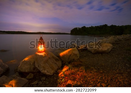 Blue Springs Lake located outside of Kansas City, Missouri at night with a lantern glowing light onto the rocky shoreline