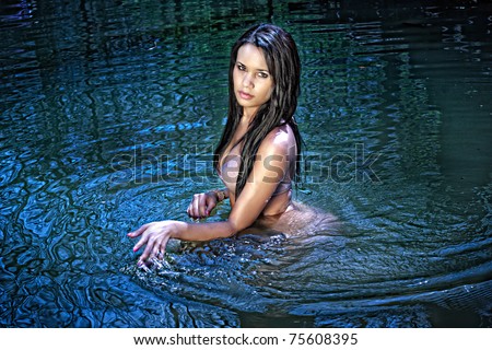 A young female playing in a deep pool of water in a creek.