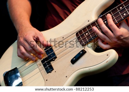 Hand of bass player while playing bass, colorful background