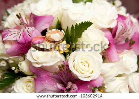Gold wedding rings of the groom and the bride on a bunch of flowers.