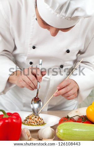 Woman chef puts vegetables on a plate