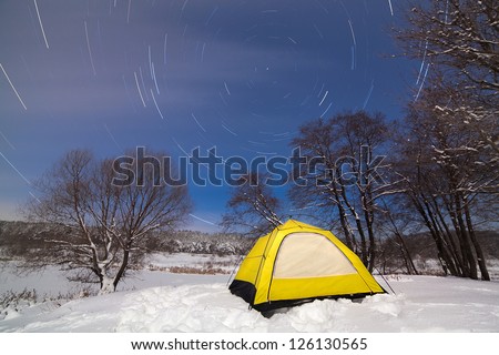 Tourist tent in the snow, on the starry sky.