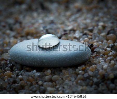 Stone with water drops on beach sand