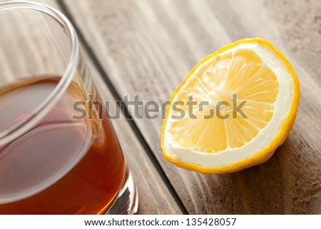 The glass with alcohol and a lemon costs on a wooden table