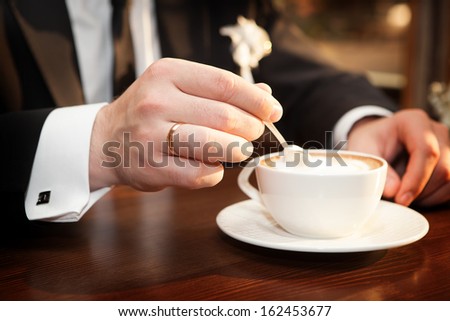 Man stirs sugar in a cup of coffee