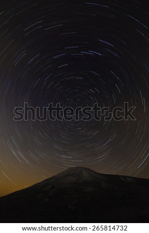 Trail of stars around the pole star on top of the mountain background.