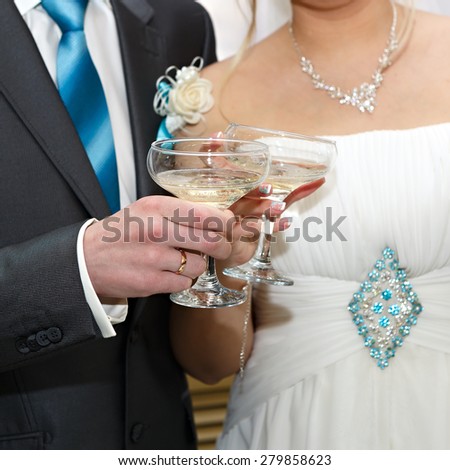 Glasses of wine in the hands of the bride and groom at a wedding party.