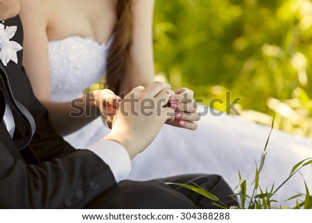 At the wedding, the bride putting on the ring on the groom\'s finger. Hand of the groom and the bride with wedding rings at a wedding party . Outdoors
