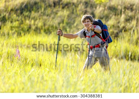 Traveler with a backpack and hiking sticks. Woman traveler goes through the tall grass. Photographed in Russia.