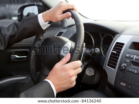 Hands of the man on a car wheel