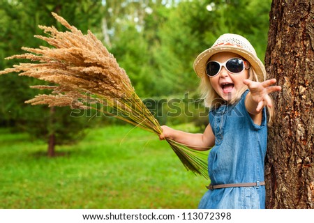 Screaming funny girl in hat with grass in hands