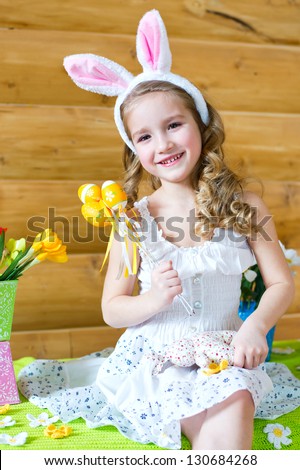 Happy easter bunny girl with easter eggs sitting in country house and celebrating easter