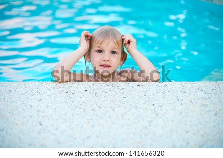 Portrait of funny little girl in swimming pool having fun