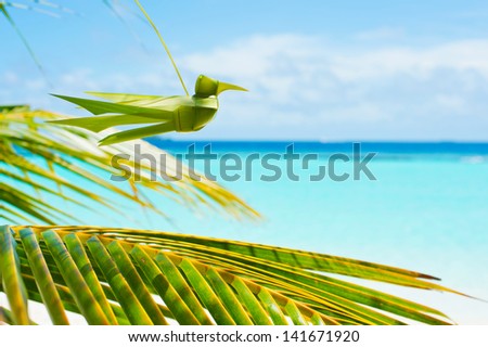 Handmade from palm leaf bird on turquoise sky