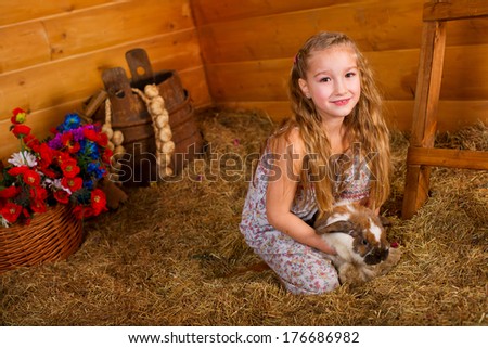 Beautiful happy girl with long blond hair playing with funny easter rabbit in hay in country house