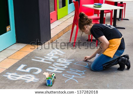 NEW YORK CITY - MARCH 30: A waitress at a bars/restaurant advertises their happy hour offerings on the sidewalk with chalk on March 30, 2013.  There are approximately 26,000 bars/restaurants in NYC.