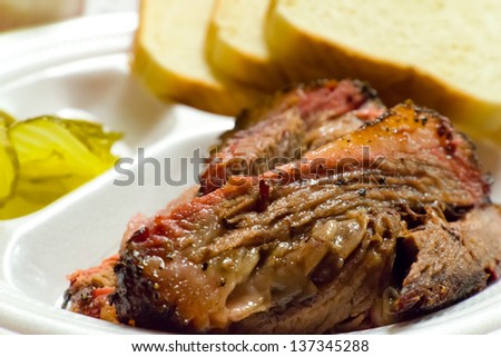 Close up of a fatty barbecue brisket picnic plate, including white bread and pickles.