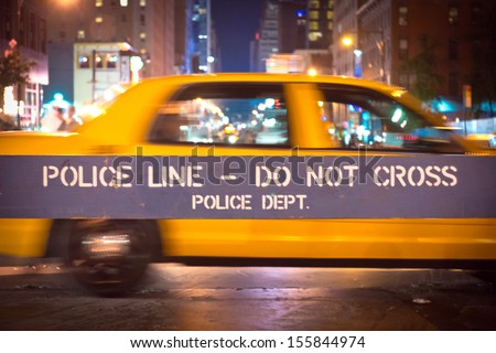 New York City police blue barricade to control traffic, with yellow taxi in background