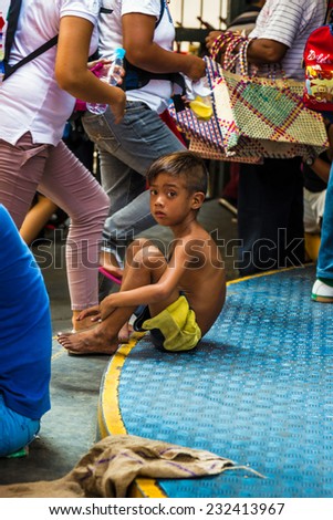 MANILA - APR 27: A young boy sits on stairs among shoppers in Divisoria in Manila, Philippines on April 27, 2014.  Divisoria is the country\'s largest outdoor shopping area.