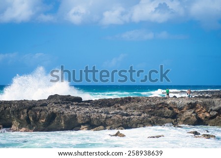 People watch large surf crashing on rocks on Oahu\'s north shore at Haleiwa, Hawaii