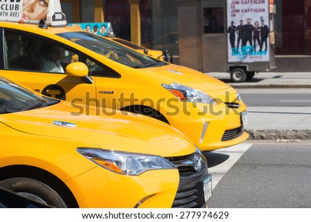 NEW YORK - APRIL 5, 2015:  Row of hybrid technology yellow cabs at a stop light in New York City.  More and more hybrid fuel cars are entering the taxi cab fleet in NYC.