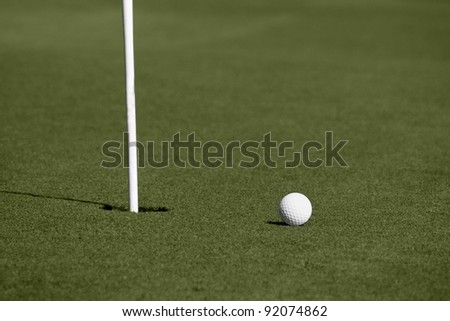 A golf ball approaches and stops near to the hole on the green.