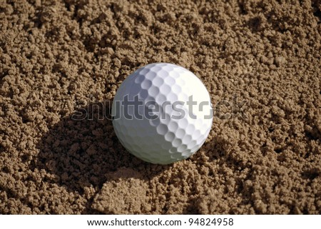 Golf ball lies in the sand trap.