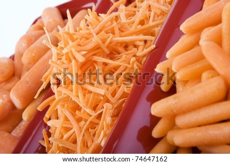 Variety of raw carrots in red ceramic dish.