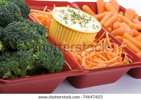 variety of raw carrots and broccoli in a red ceramic dish with ranch dip.