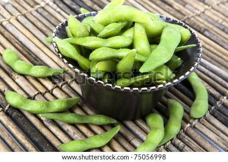 Edamame soy beans in a brown ceramic dish.