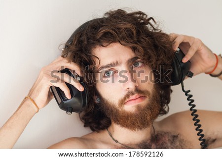 Relaxed young guy at home listening to music with headphones