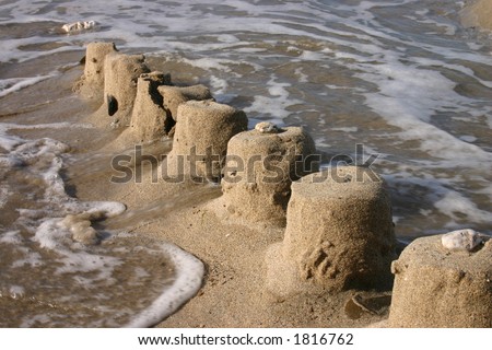 The ruins of a sand castle being swept away by the sea