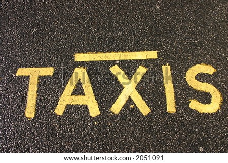 Yellow taxi sign on black tarmac