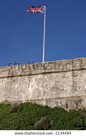 The Union flag (Union Jack) flying above an old fortress wall, Plymouth, Cornwall, UK