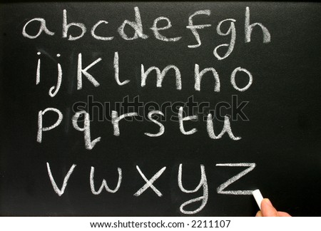 Writing the alphabet with chalk on a teacher\'s blackboard.