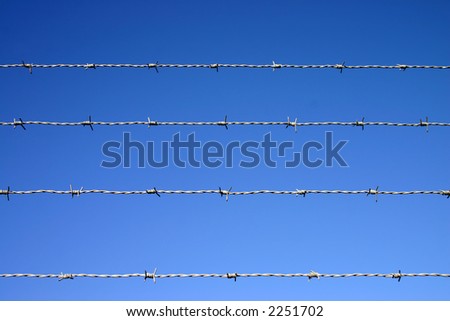Four lines of barbed wire fence against a blue sky