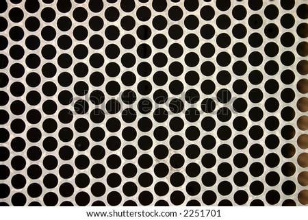 Close up of a metal fence with round holes, makes an interesting abstract background.