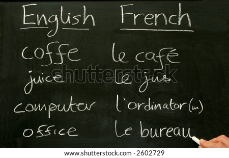 A teacher writing French lesson words on a blackboard.